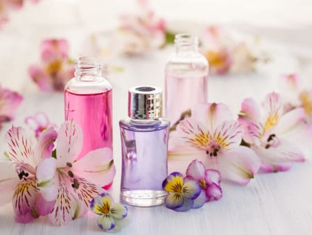 Bottles of essential aromatic oils surrounded by fresh flower